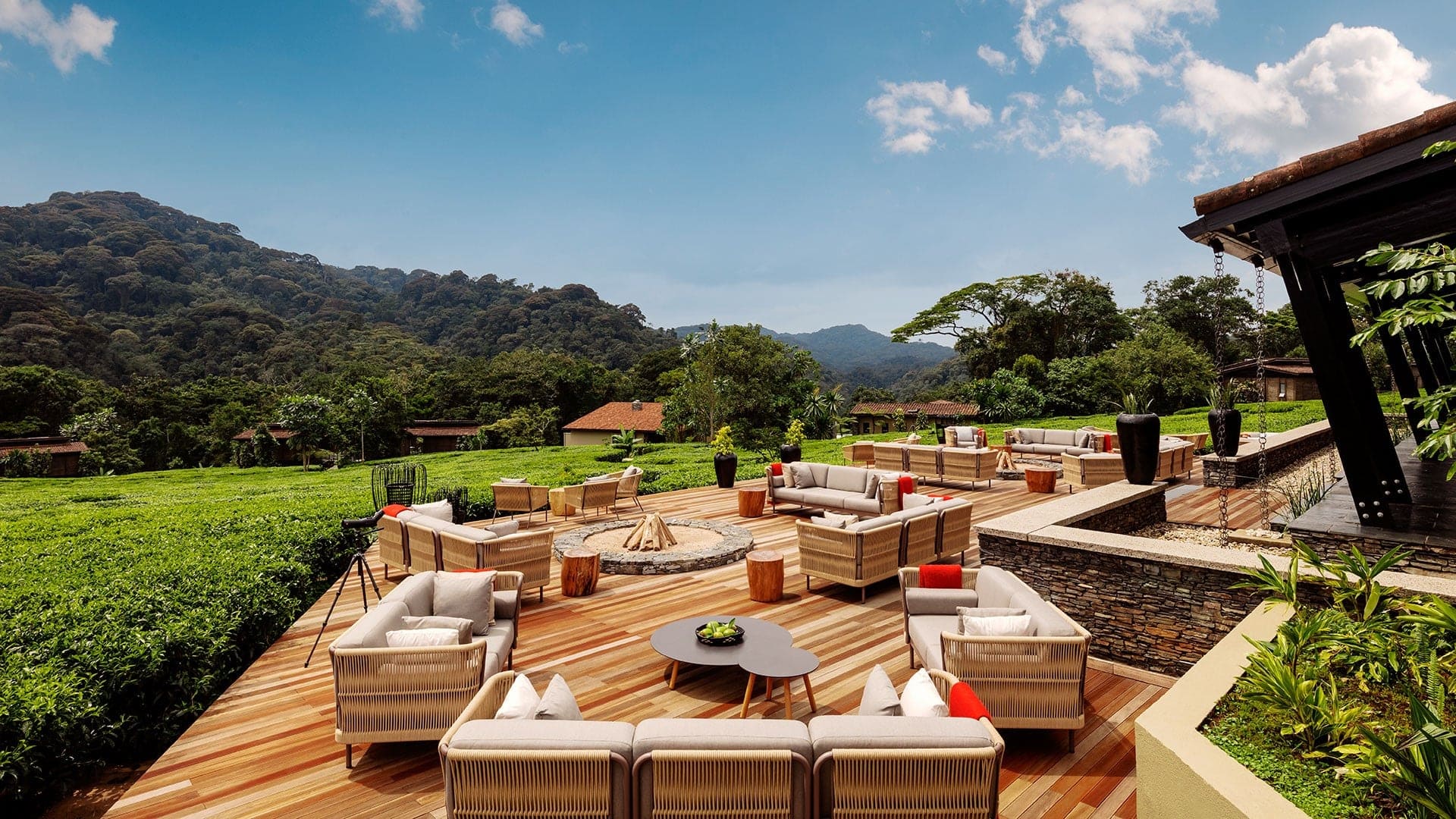 Outside dining area with couches and campfires with nature surrounding it