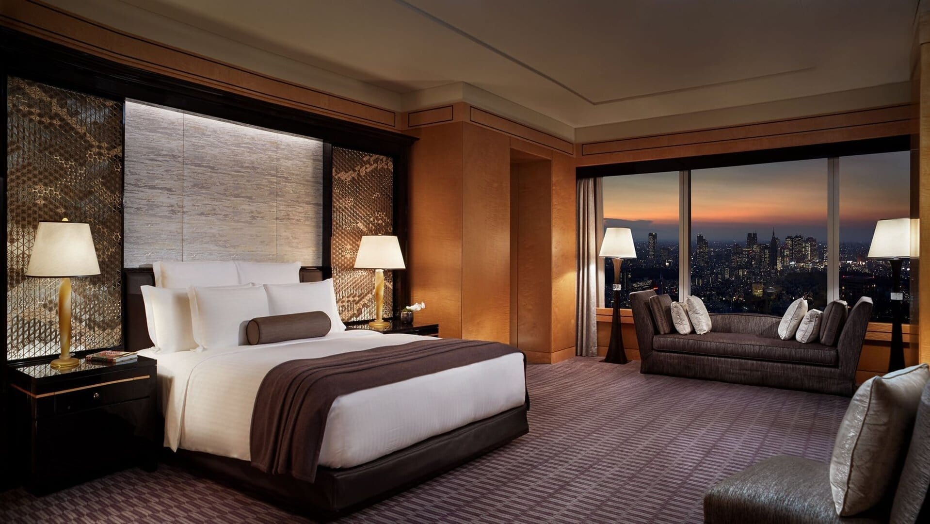 Sleeping area with white and brown carpets, blach night bed, sofas and chairs with modern design and stunning view to the city.