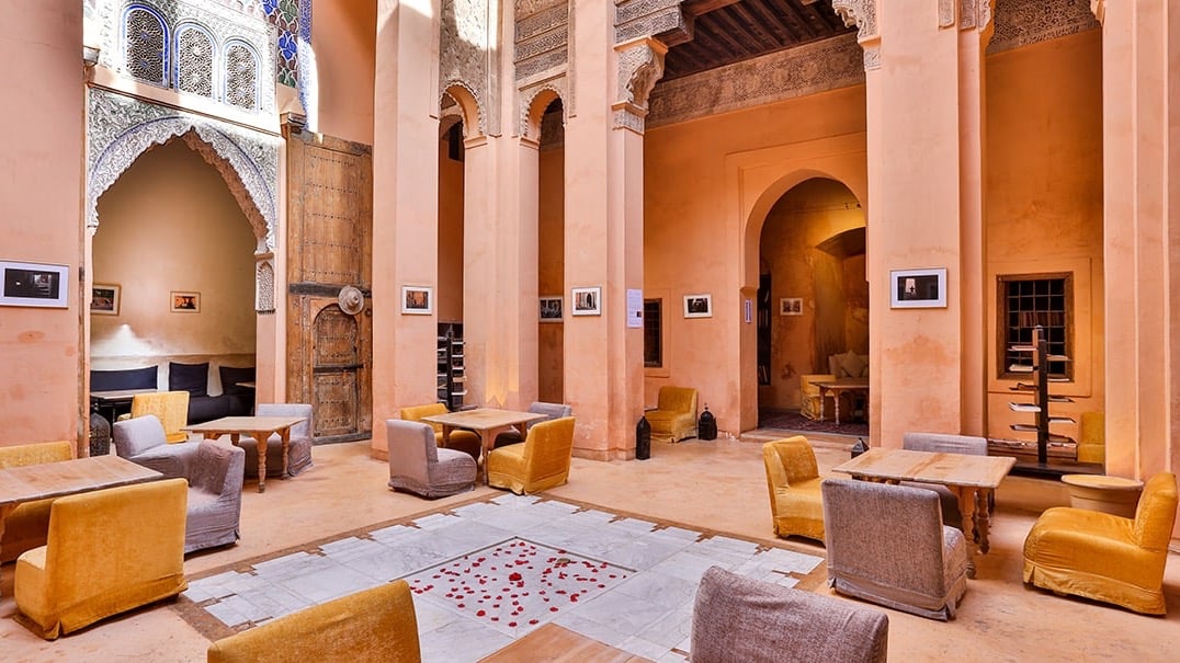Cafe and gallery space with curved beams, Orange and purple furniture and orange walls, with small paintings.