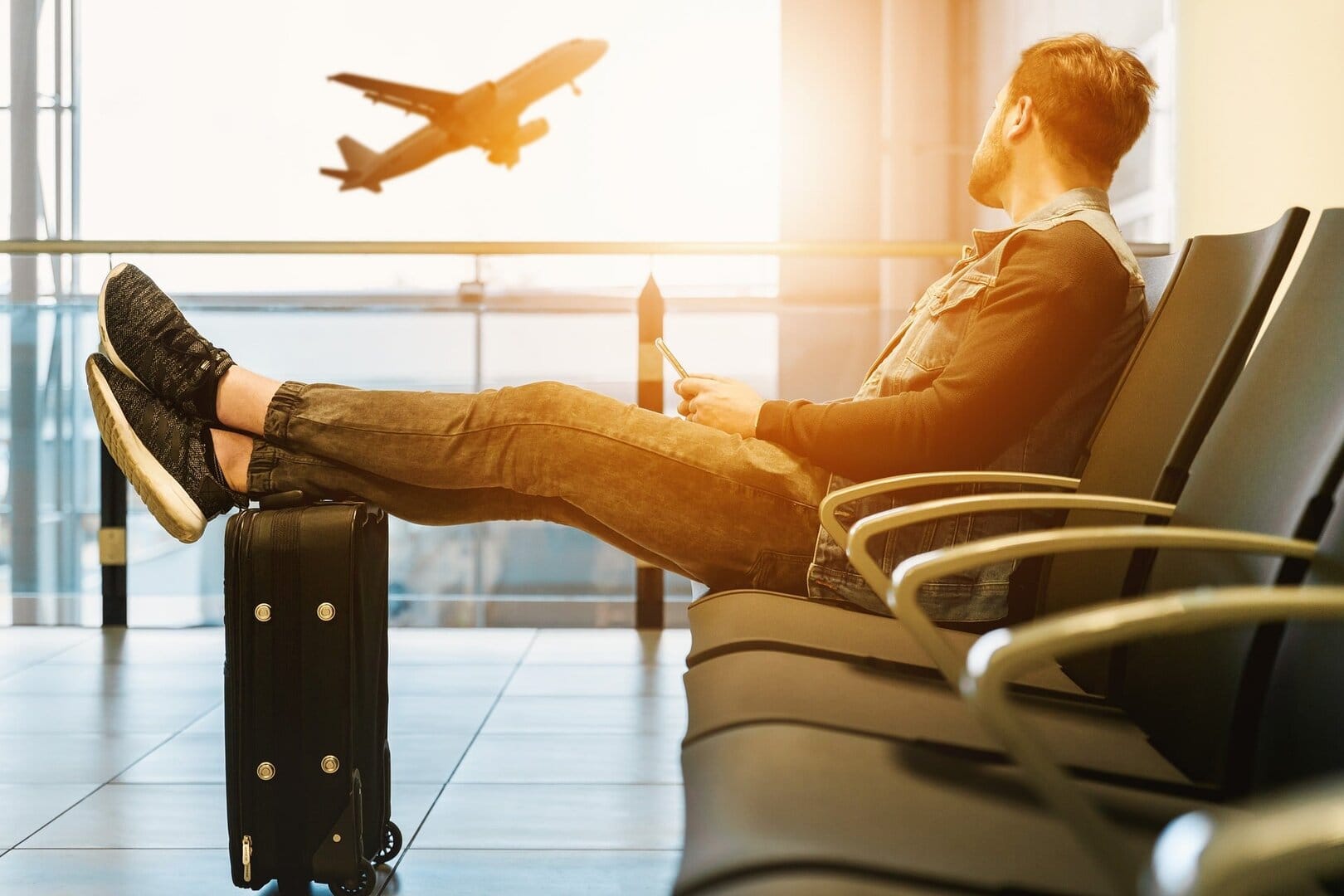 Man lading back in a chair with his feet on his luggage