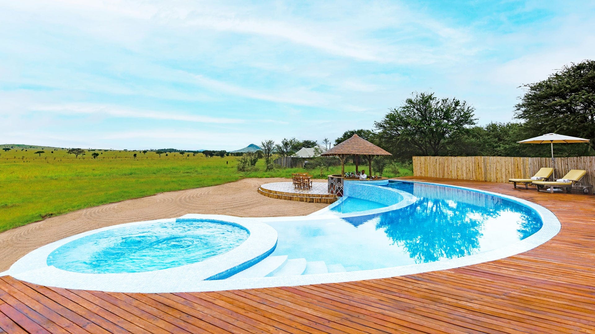 Pool with sunbeds in wooden style with open view to the savannah