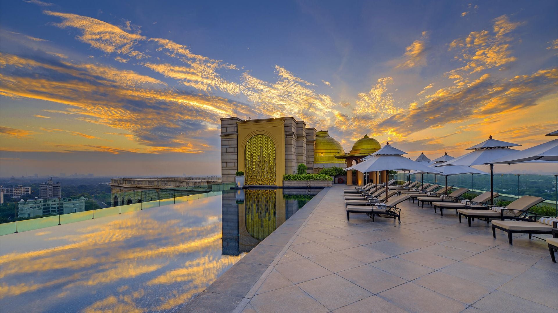 Rooftop pool area with sunbeds and view to the city at Leela New Delhi