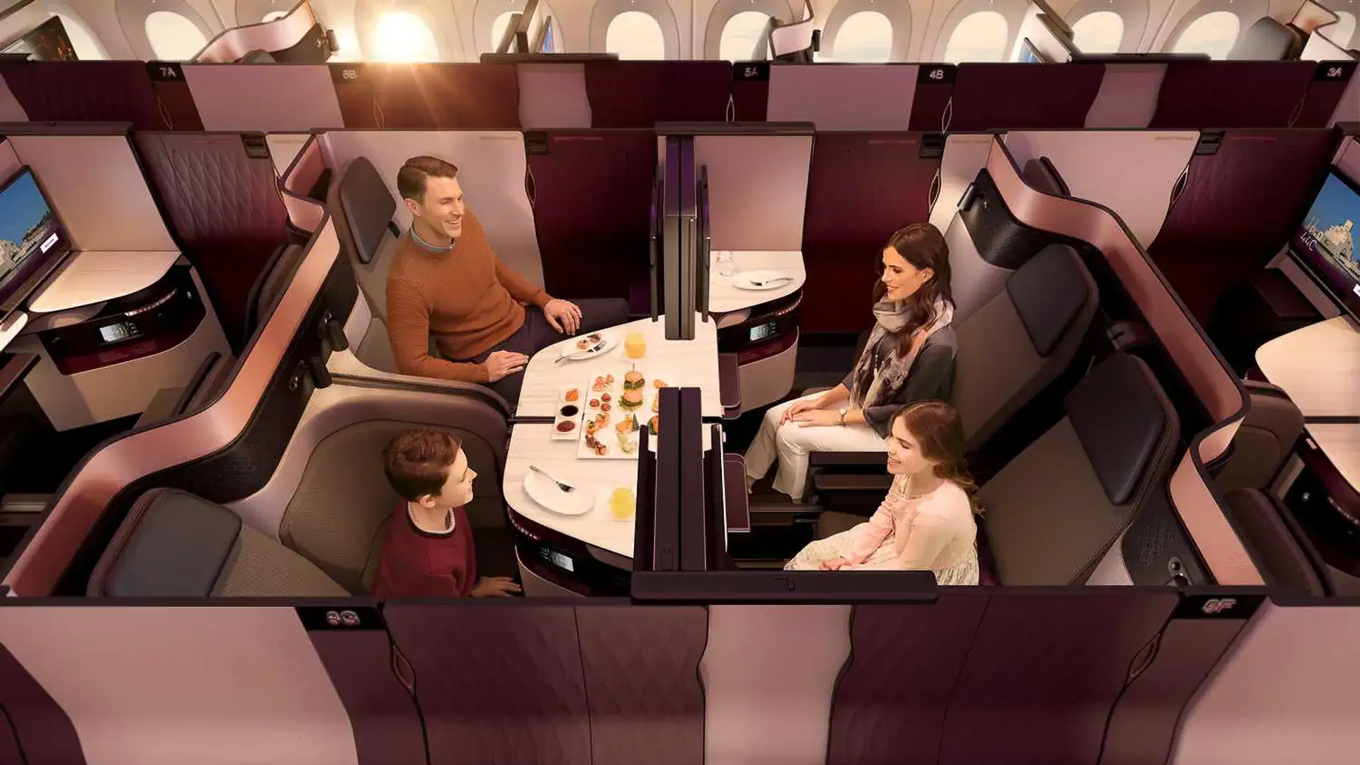 a family of four getting ready to eat in their qatar airways business class seats