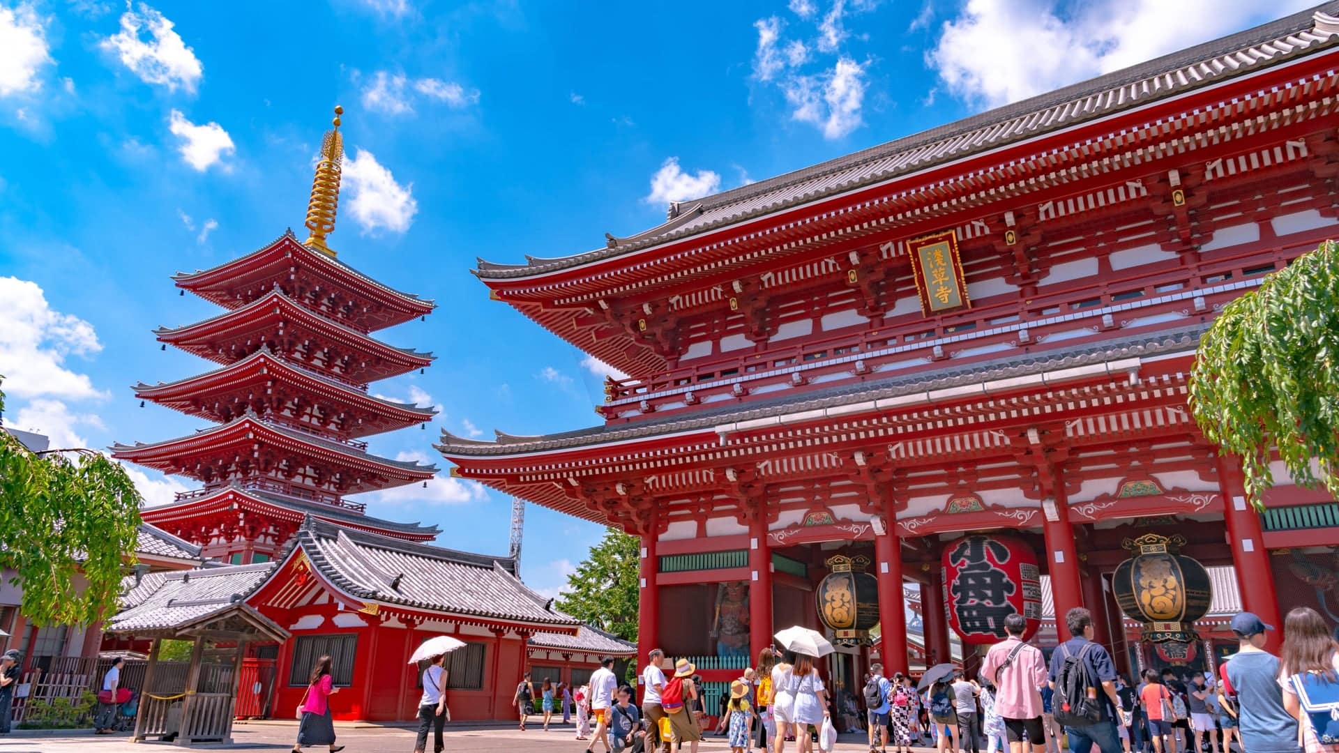 Red temple surrounded by crowds, and red temple tower calles Kaminarimon Gate.