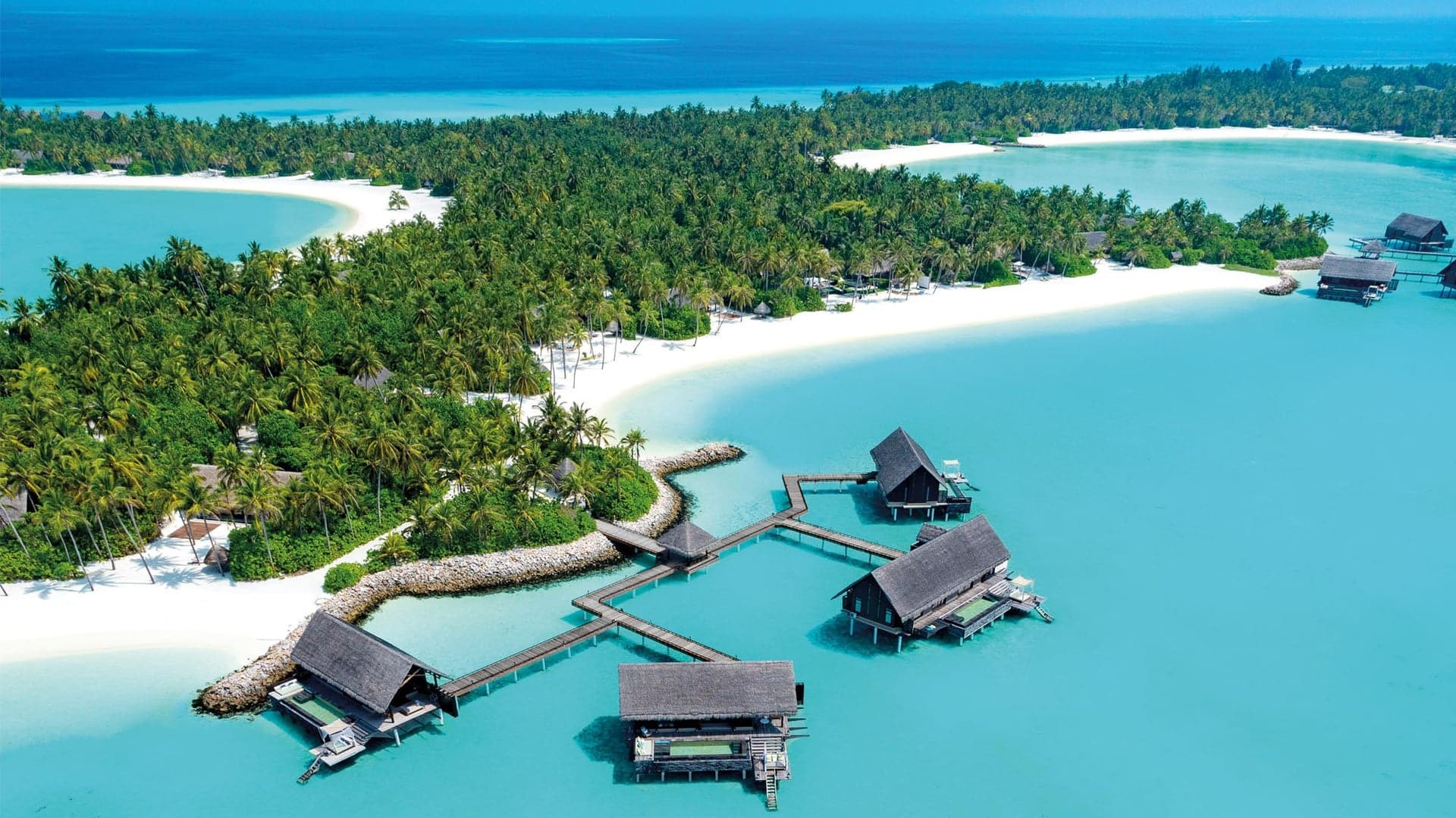 Bird perspective of extension suite cabins, blue water, a lot of palm trees.