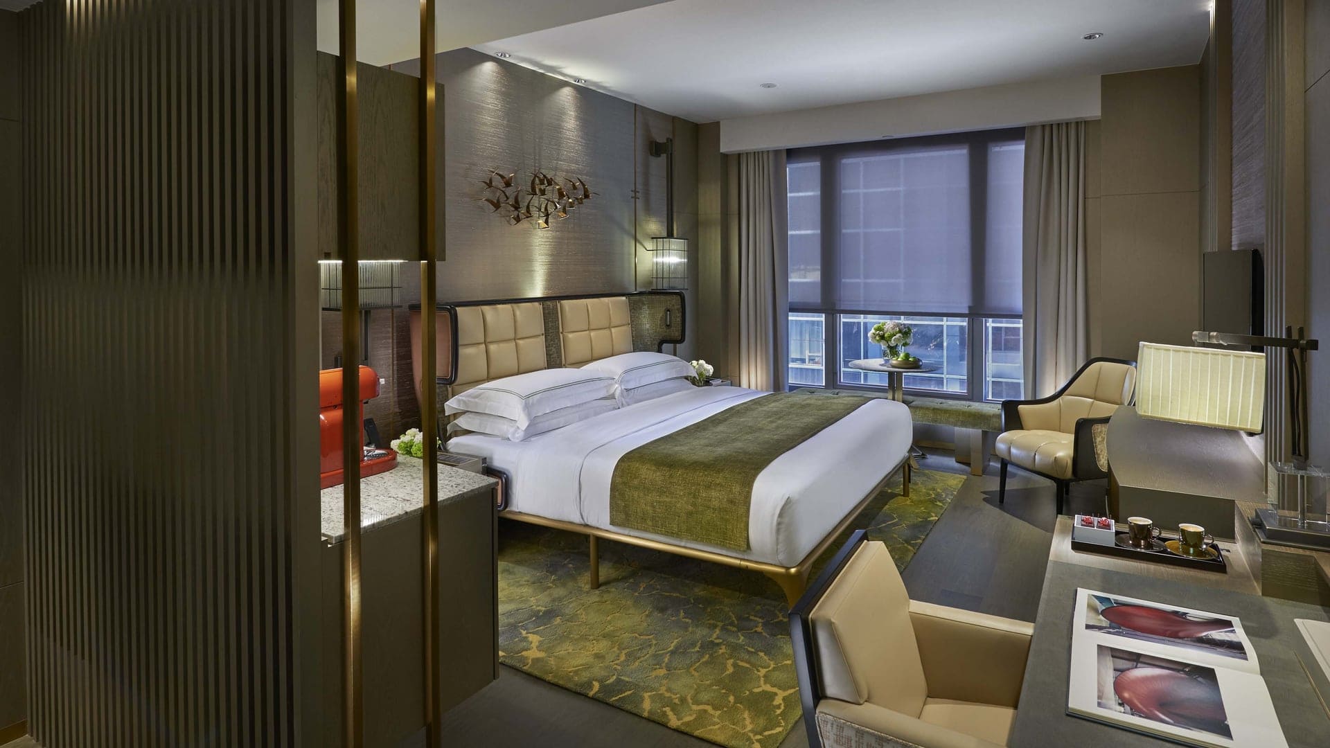 Hotel room at Mandarin Oriental, kingsize bed, green carpet, nature look, large window, chairs, and a coffee machine.