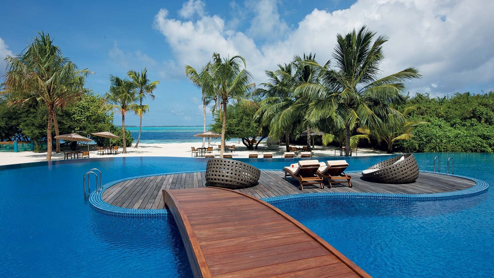 Pool area with wooden bridge at Lily Beach Resort å Spa at Huvahendhoo, Maldives.
